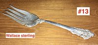 Full length photo of Wallace sterling silver serving fork showing ornate handle and broad tines.
