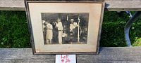 Full view of the framed 1930s jazz band photograph on wooden bench outdoors with label 'Lot #26'. The photo features five musicians on stage.
