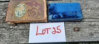 Three autograph albums displayed on wooden surface, showing ornate covers and general condition