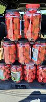 14 clear plastic containers filled with red silk Christmas ball ornaments, stacked in a vehicle trunk.