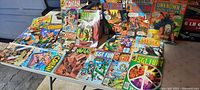 Photo of 18 vintage mixed comic books on a table showing covers of Conan, Sgt. Rock, Unknown Soldier, War, and Sgt. Fury with bright colors and mid-century comic art.