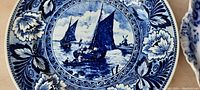 Close-up of the larger 9-inch cobalt blue plate featuring sailing ships on water with a floral border.