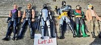 Six 8-inch action figures laid on wooden surface, showing full body detail including clothing and accessories.