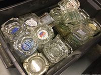 Bin containing stacked square glass ashtrays