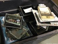 Plastic bin holding multiple glass and possibly plastic ashtrays, some with promotional images and logos visible.