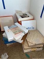 Stack of boxed collectible plates including Dorothy's Day and other labeled boxes with Styrofoam protection for the plates inside.