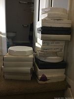 Stack of fourteen white and grey Styrofoam and cardboard boxes containing decorative plates.