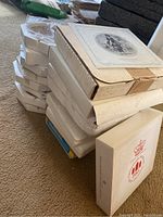 Stack of boxed collector plates on carpet floor, various brands and packaging styles visible