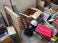 Photo showing multiple stacked puzzles, games and model kits with a helmet and some kneepads, boxes and packages overlapping