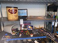Shelf contains toy cars scattered in a white container and on the shelf, Charlie Chips potato chip tin, puzzles and framed airplane picture on upper shelf, and Buffalo flag
