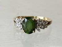 Front view of the 14K gold ring showing oval green center stone and diamond side accents.