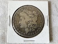 Obverse side of 1884 Morgan silver dollar coin showing Lady Liberty profile and date.