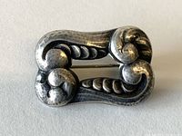 Front view of antique Danish sterling silver pin showing decorative scroll and leaf design.