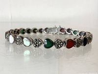 Front angle of the tennis bracelet showing the hearts with multi-stone inlays: carnelian, marcasite, onyx, and abalone, plus clasp.