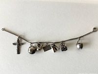 Full view of the 7-inch sterling silver charm bracelet with all seven charms visible from left to right.