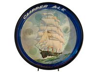 Top-down close-up photo of the round metal tray with clipper ship image and blue rim with "CLIPPER ALE" text.