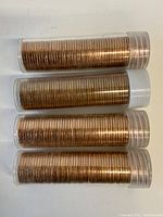 Four plastic tubes filled with copper-colored pennies stacked horizontally.