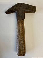 Front view of small antique forged hammer showing metal head and wooden handle