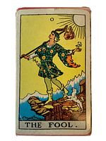 Front side of the box showing The Fool tarot card artwork with figure in flowered tunic and dog on cliff, labeled 'THE FOOL'.