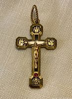 Front of metal crucifixion cross pendant with Jesus figure and medallions.