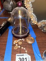 Glass display dome, pocket watch and bracelet arranged on table