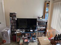 Wide view of black media shelving and adjacent rack loaded with CDs, box sets, DVDs and a TV unit