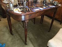 Angled side view showing the table's turned legs, curved edges, and scratches on the tabletop.