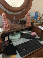 View of wooden dresser top with two terracotta child figurines, decorative boxes, perfumes, and hairbrush