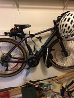 Left side view of Kona Libre bicycle hanging on wall rack showing frame, saddlebag, helmet and battery pack.