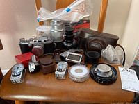 Group shot of Leica camera, four lenses, leather case, two meters, and lens cap