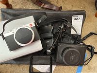 Full kit laid out showing camera on box, leather case, flash, charger, cable and strap