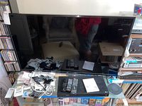 Full view of LG 43-inch TV with remote and BluRay player on shelf with cables and accessories.