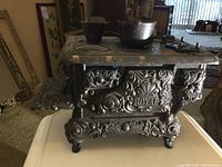 Front quarter view of the cast iron Royal toy stove showing ornate design and accessories on top.