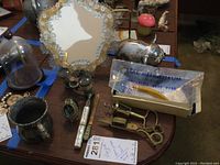 Overview of lot showing opera glasses, mirror, metal piggy bank, silver plate cup, corkscrew, decorative egg, and pipe in original box