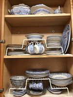 Full view inside a cabinet showing stacked Ridgways dinnerware including cups, plates, bowls, and serving pieces all in the classic blue and white pattern.