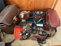 Overview of all items on shelf including camera, cases, bags, light meters, manuals, straps