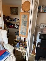 Photo showing the side table with items arranged on top including metal bucket, flags, scissors, boxes, and string of bells, with hanging bamboo scroll visible on adjacent wall