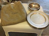 Gray suede pouch and two stacked round bowls on white stool