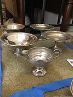 Group shot of four footed bowls and one creamer