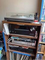 Four stacked audio components on wooden shelving