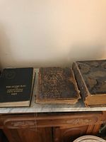 Photo showing all three vintage books together on a table: The Lucky Bag book on the left, two worn Holy Bibles to the right.