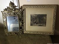 Photo showing both the ornate framed mirror with stand and the framed print side by side on the floor.