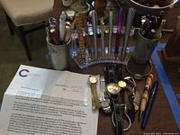 Overview of lot: watches laid out with pen cups and acrylic holder behind