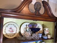 Image of vintage and Wedgwood dishware and glassware displayed on wooden shelf with decorative top.