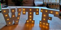 Front view of white wood letters W, T, F with embedded lights turned on