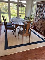 Full view of cream rug with navy blue border under dining table and chairs