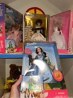 Photo showing three Barbie dolls in original boxes: Dream Wedding Barbie, Winter Classic Barbie, and Wizard of Oz Dorothy Barbie with book.