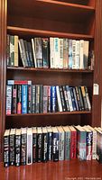 Shelf of hardcover and paperback books including Ken Follett novels and assorted thriller books