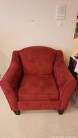 Front view of red upholstered armchair showing seat cushion, armrests, and backrest