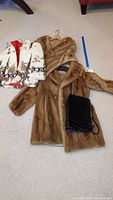 Full view of four items comprising two brown mink fur outerwear garments, child's white and brown rabbit fur jacket with floral trim, and black crocodile handbag